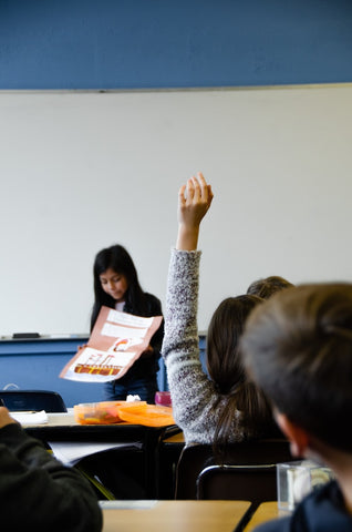 une fille lève la main en classe