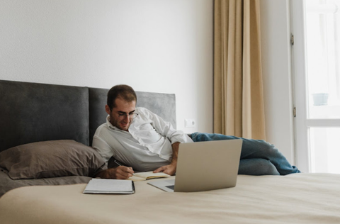man working on his laptop in his bed