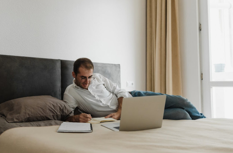 hombre trabajando en su computadora portátil en su cama