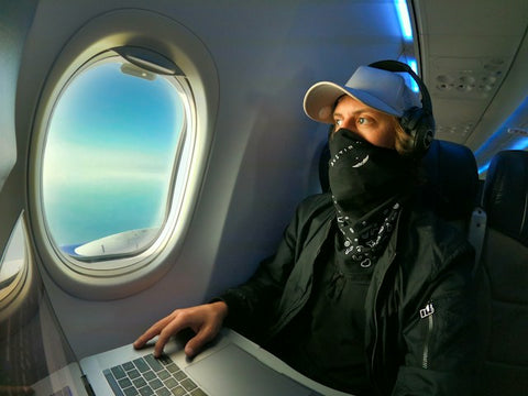 man in black jacket and black cap using laptop in plane