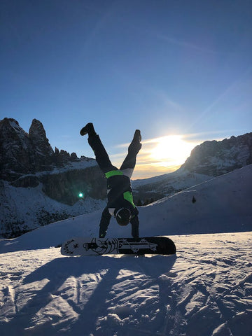 Mann macht Handstand in der Nähe des Snowboards