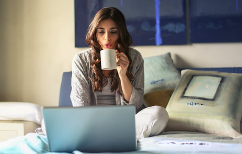 コーヒーを飲みながらラップトップで何かをする女性