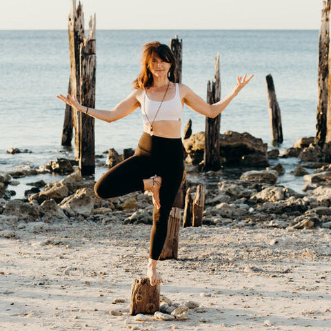 Mid standing in a yoga pose at the beach.