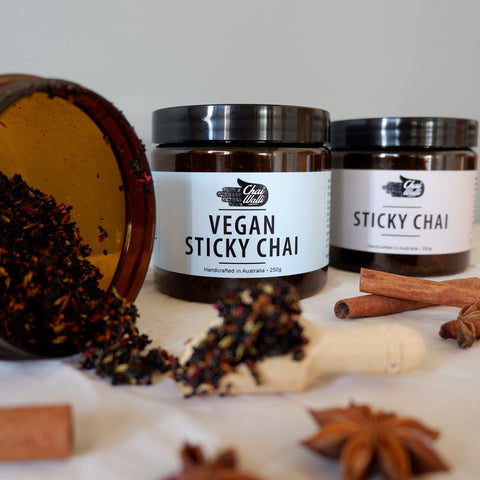 Chai Walli sticky chai and vegan sticky chai in amber jars, with cinnamon and spices in front.