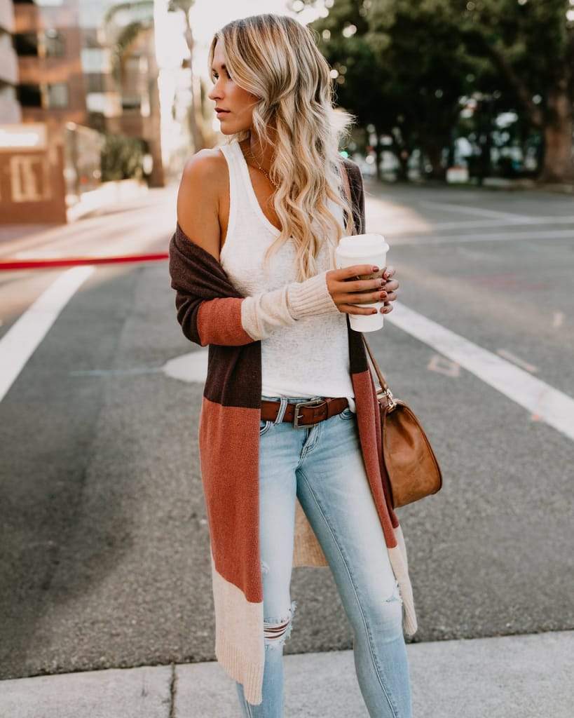 a woman holding a bag and walking on a sidewalk