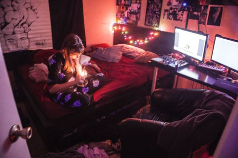 A woman sitting in her room smoking a bong