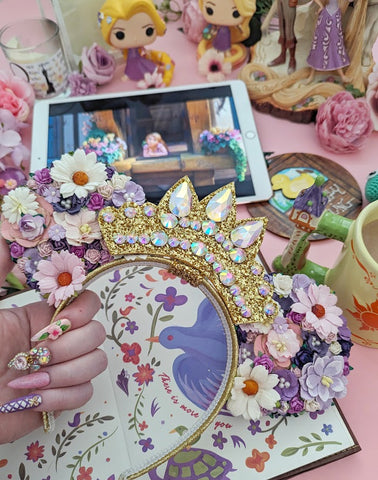 floral mickey mouse ears with gold glitter tiara surrounded by Tangled merch and the tangled movie in the background