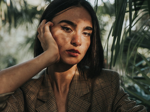 Woman wearing an environmentally friendly blazer in the shadows of a tree