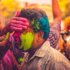 hand smearing Holi colors on the forehead of a man