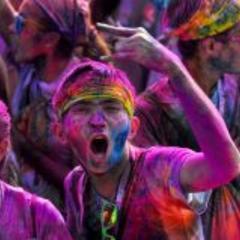 man celebrating Holi with colors spread all over him in a crowd