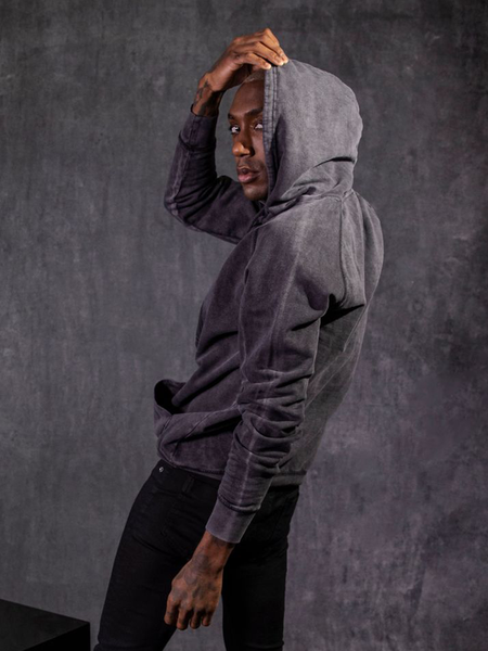 With his hood pulled mostly over his head, Braxton Holmes looks back at the camera while modeling a gothic style outfit featuring the Alien™ Retro Poster Logo Hoodie.