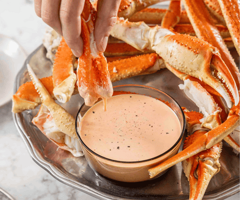 Cooked Snow Crab recipe being dipped into sauce