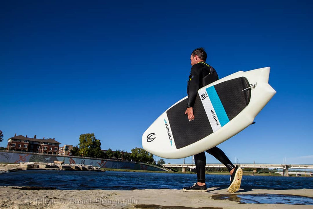 Surfer carrying a Badfish river surfer board