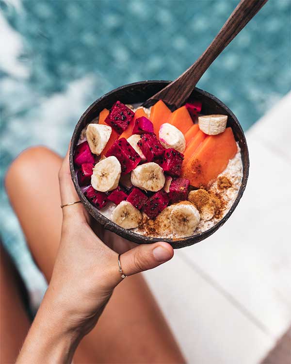 A close up of a woman holding a healthy fruit bowl