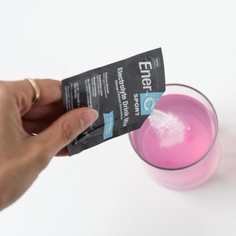 Woman pouring an Ener-C Sport electrolyte drink mix packet into her lemonade