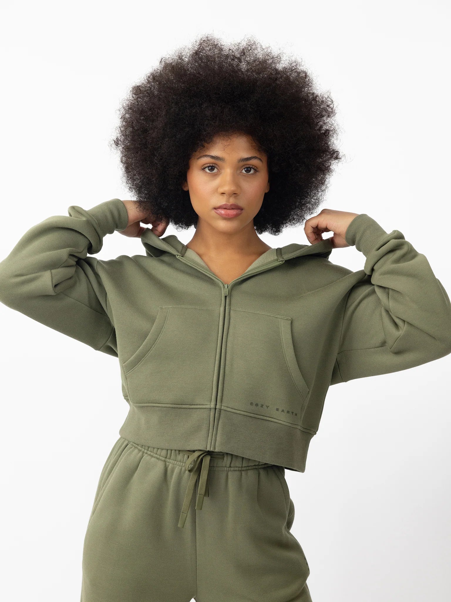 Person with curly hair wearing a green hoodie and matching pants.