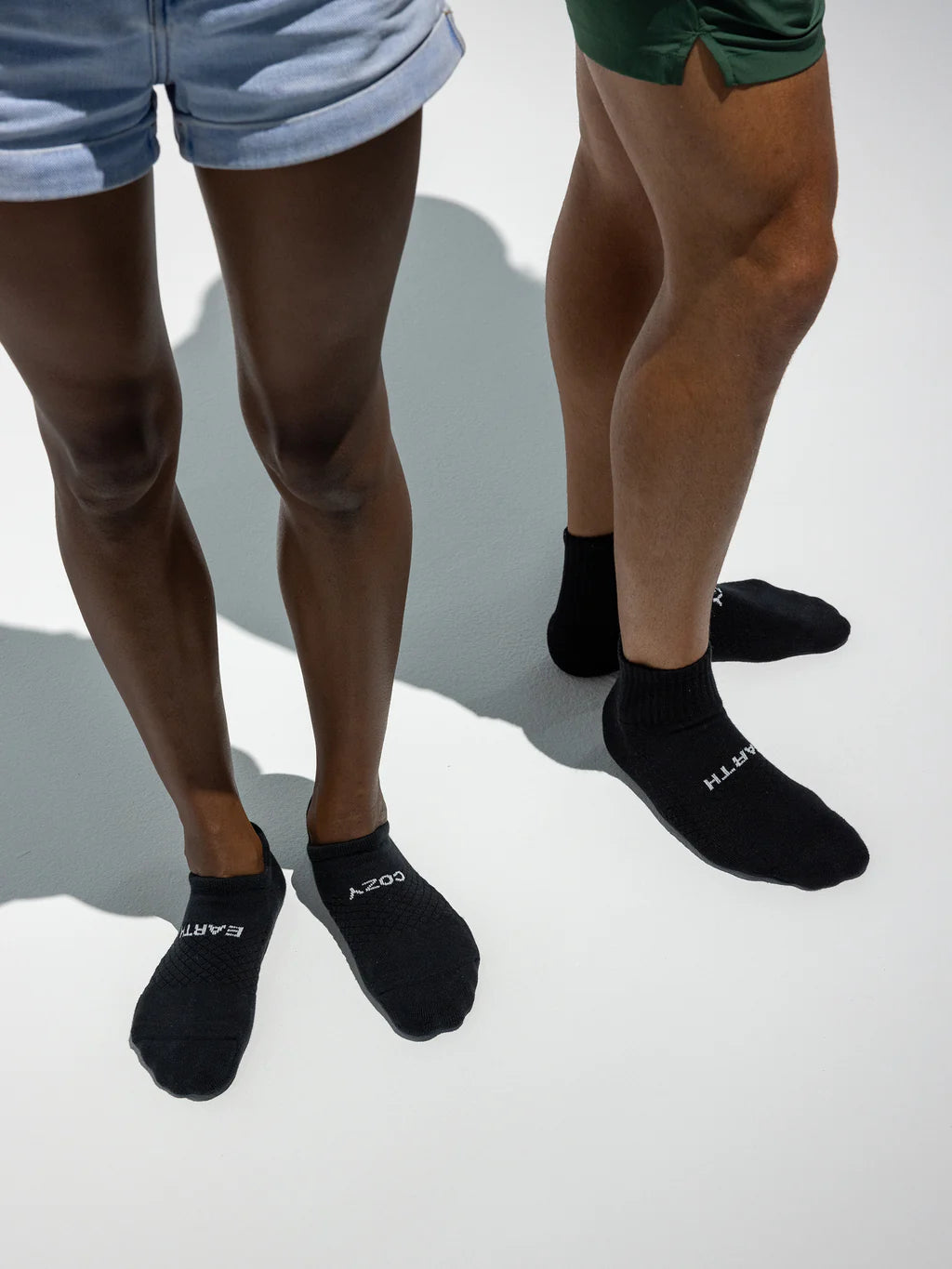Two people wearing black socks, standing on a light gray surface.