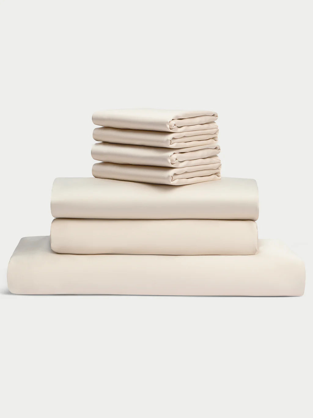 A neatly stacked set of cream-colored bed sheets.