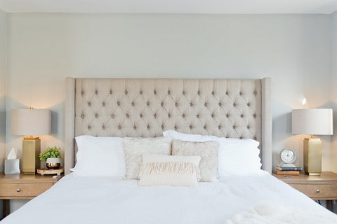 A bed with white sheets and an upholstered headboard