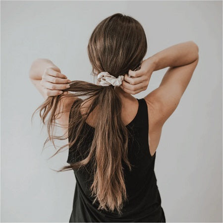 Woman adjusting hair pulled back with scrunchie