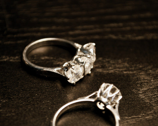 Classic engagement rings on a dark wood table.