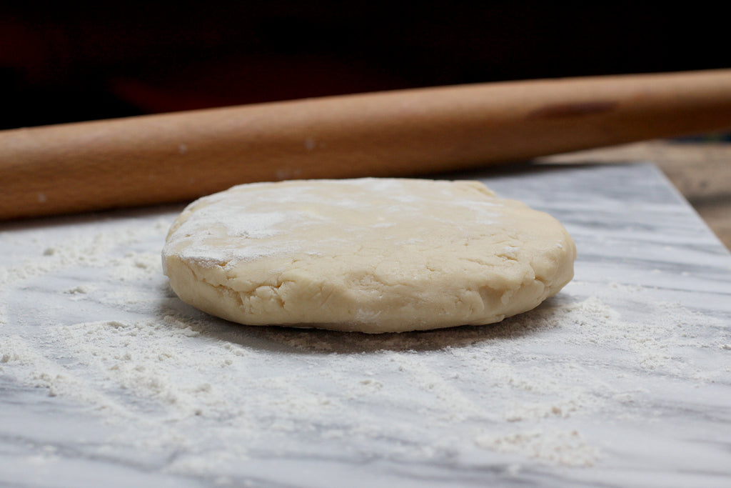 Pie dough and rolling pin on marble pastry stone