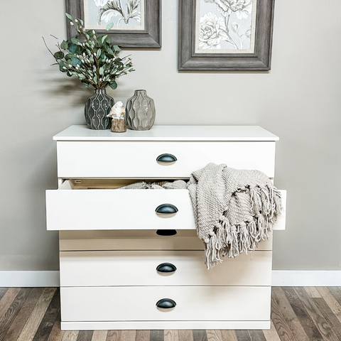 A wide, 5-drawer, unit with one drawer open, displaying a beige towel.