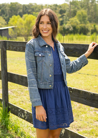 Woman wearing denim jacket over Navy Eyelet Sleeveless Dress.