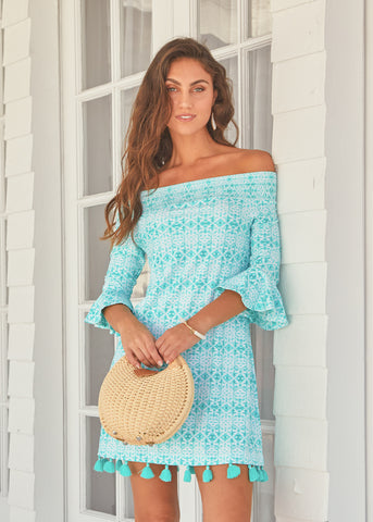 Woman wearing Sunshine Shores Off The Shoulder Dress while holding a purse.