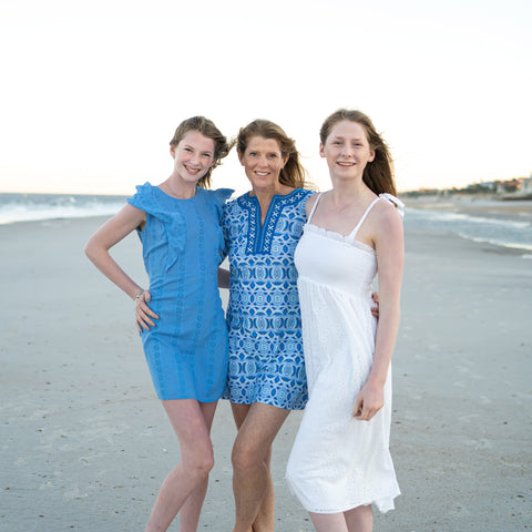 Women in blue dresses & white dress on beach