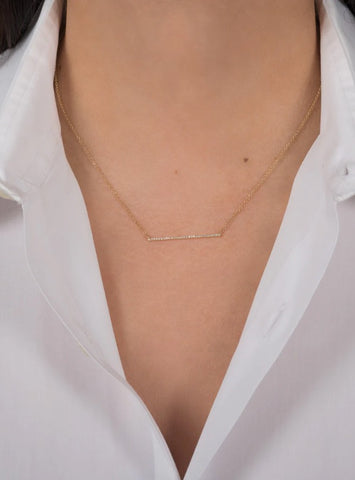 Woman in white collared shirt with gold diamond bar necklace