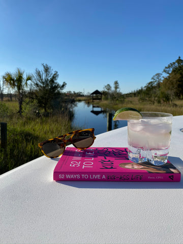Drink on top of pink book in front of marsh