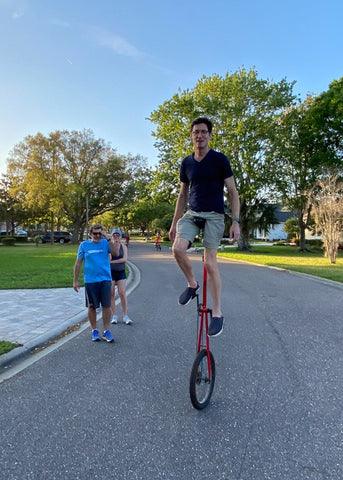 Man riding tall unicycle on sidewalk