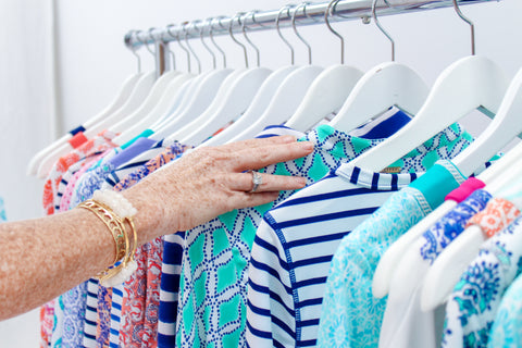 Woman's hands running through clothing rack of colorful dresses