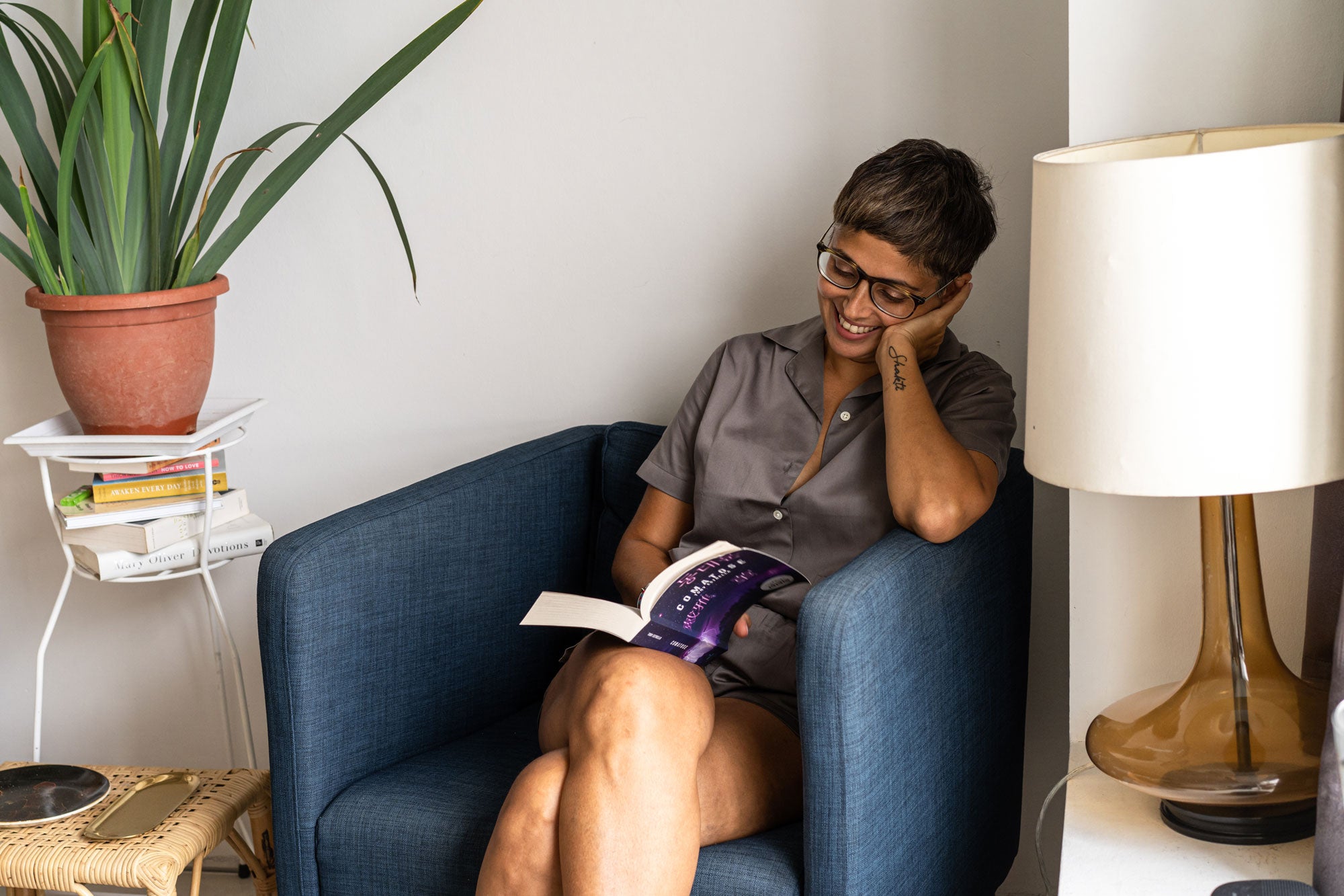 anita kapoor reading in her living room next to potted plant