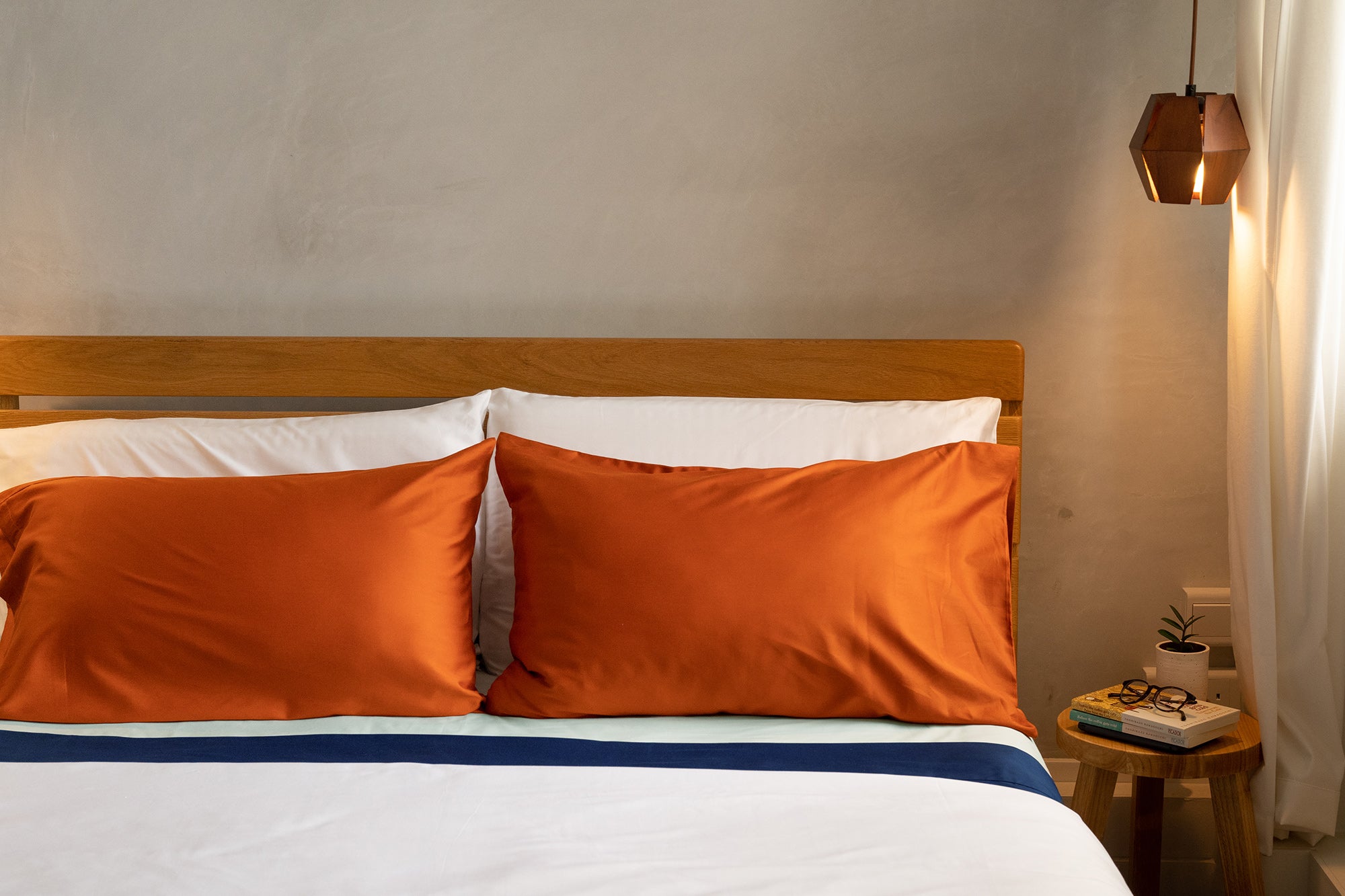 burnt orange organic cotton bedsheets against cement screed wall