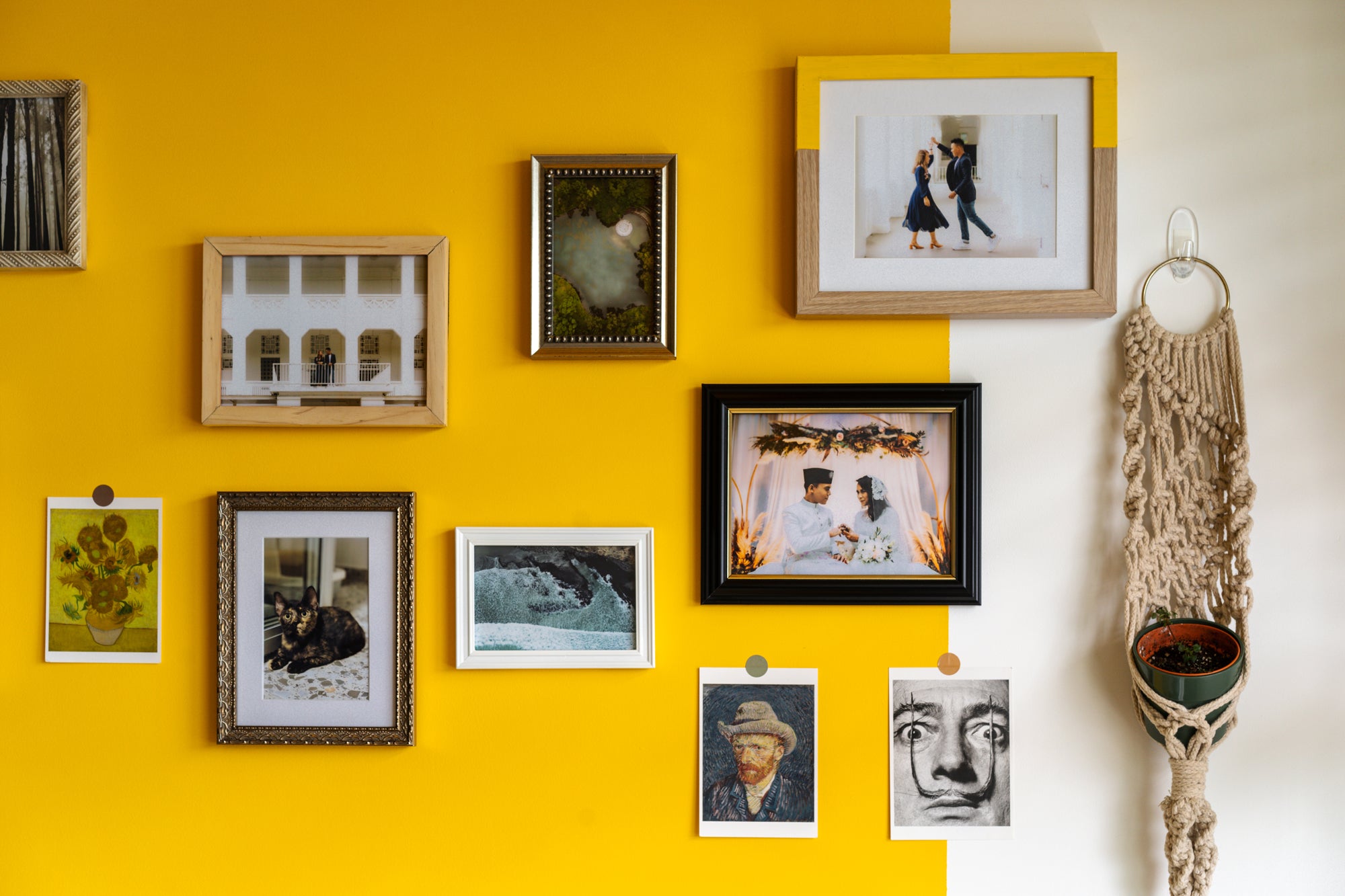 yellow wall filled with hanging photo frames and art 