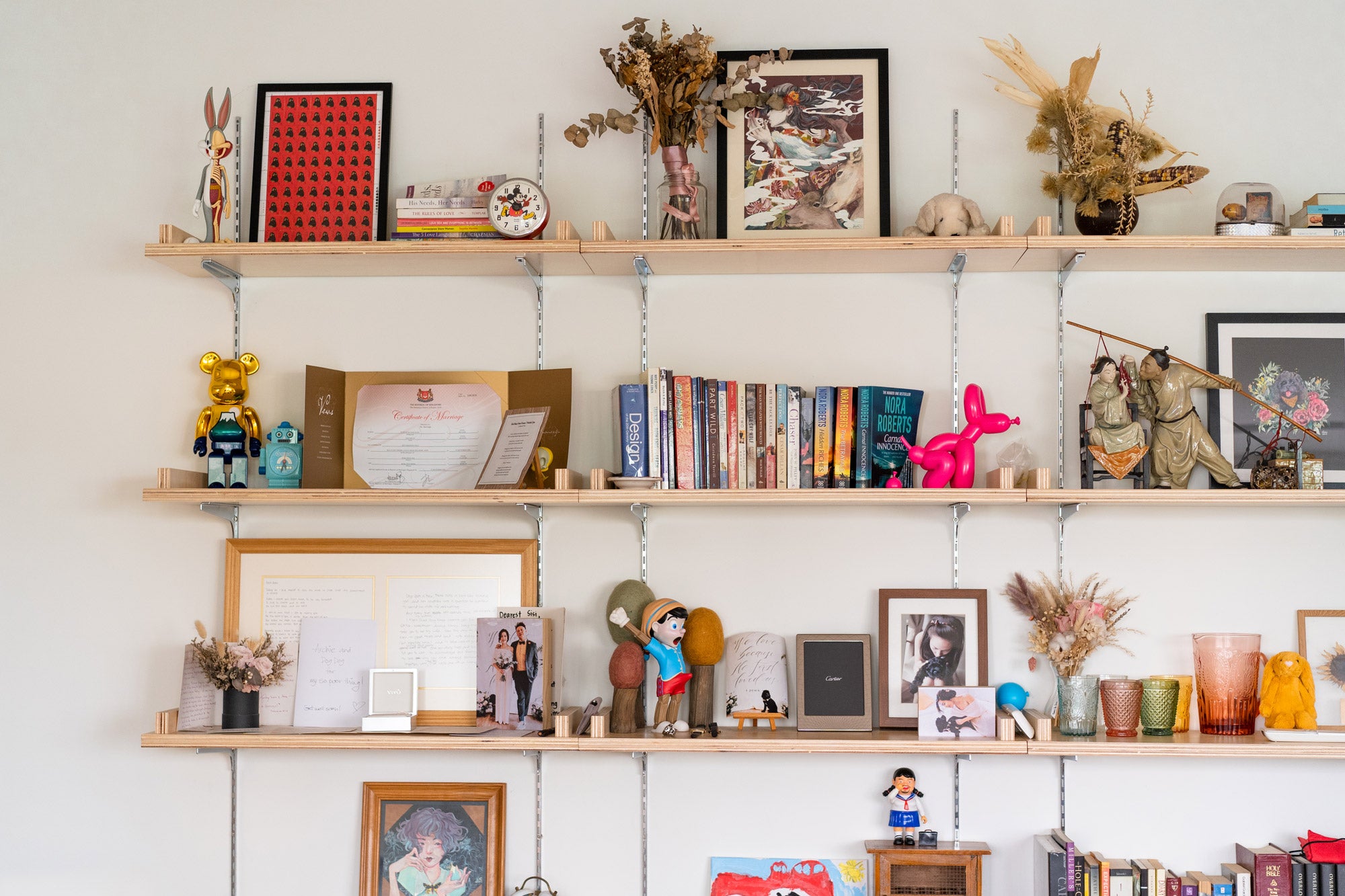 custom made wooden shelf against white wall with artworks