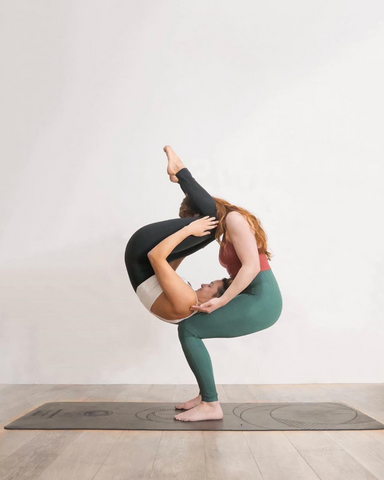 The theme of Acroyoga and Yoga Poses. A pair of two men and a woman stand  in the position of asana. The guy holds the girl arched high back on the out