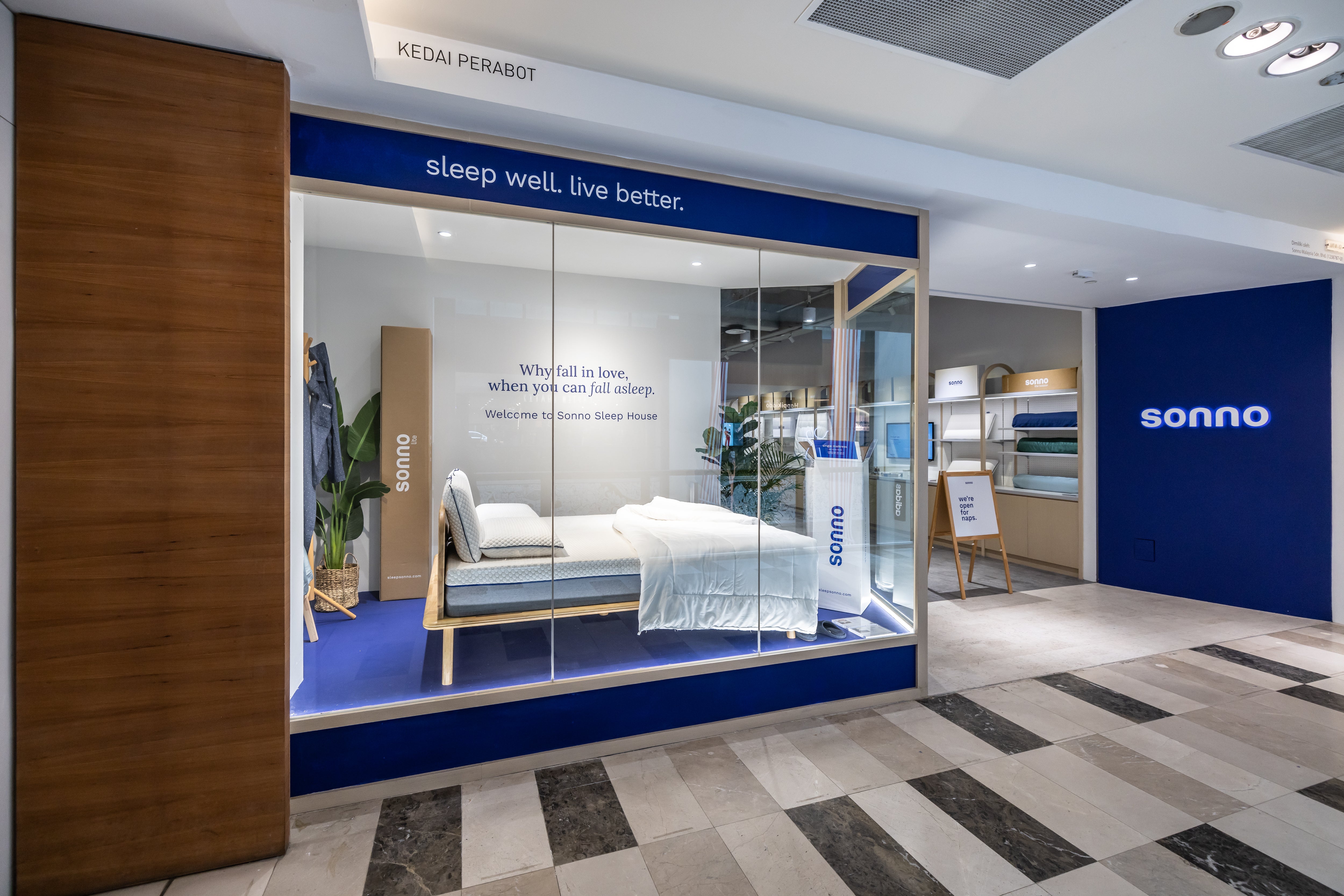 A Sonno window display with the Sonno bedframe, mattress, pillow, weighted blanket, and more, with the signage reading ‘Why fall in love, when you can fall asleep. Welcome to Sonno Sleep House.’