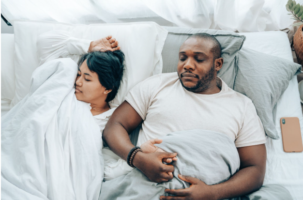  An interracial couple, cuddling in bed, in the morning light