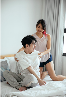 An Asian couple, chatting in bed, in the morning light