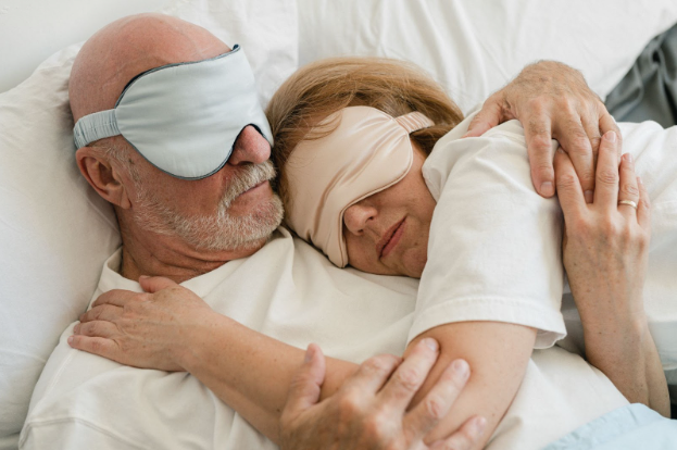 An old couple comfortably holding each other while sleeping together in bed