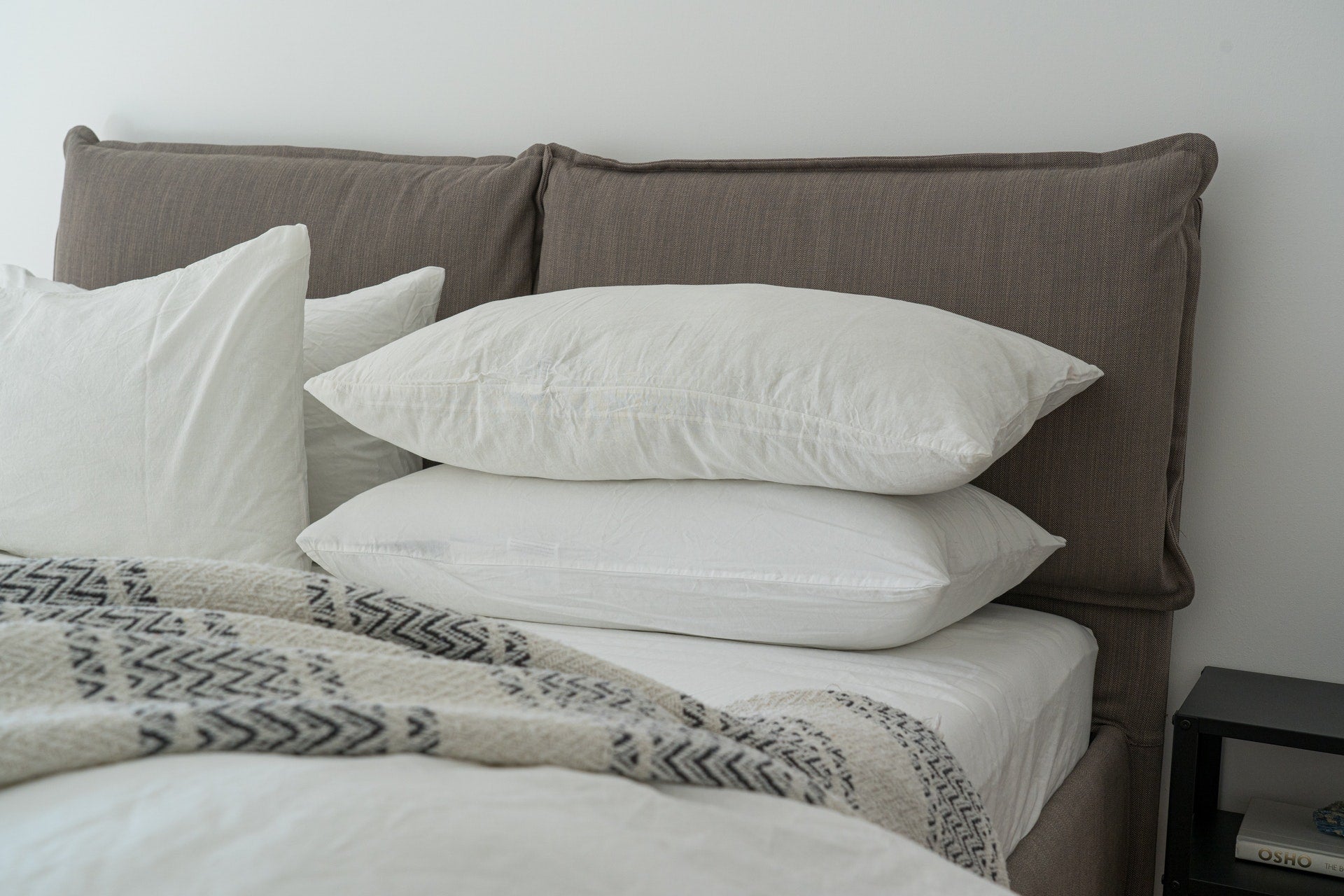 A fully furnished white bed setting with pillows, a duvet, and properly tucked bedsheets