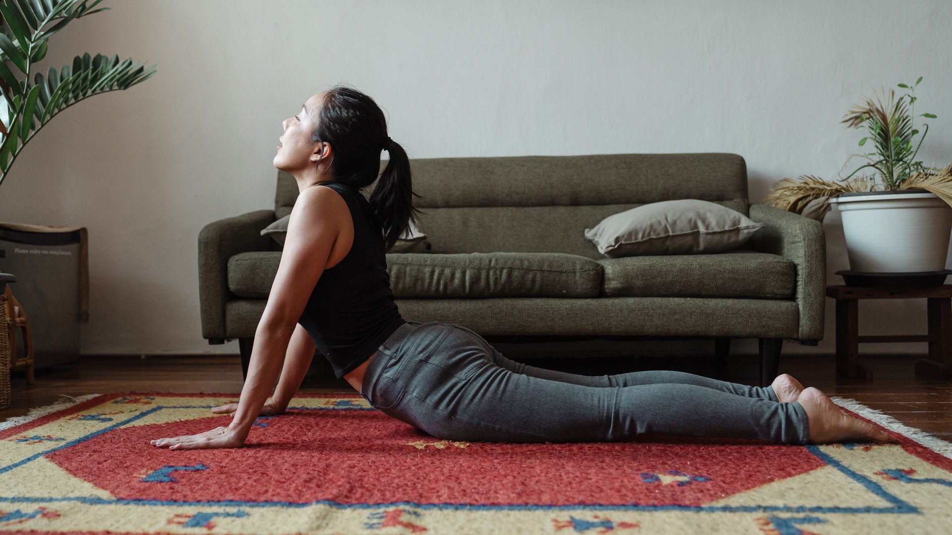 A woman stretching and doing yoga at home on top of her red carpet