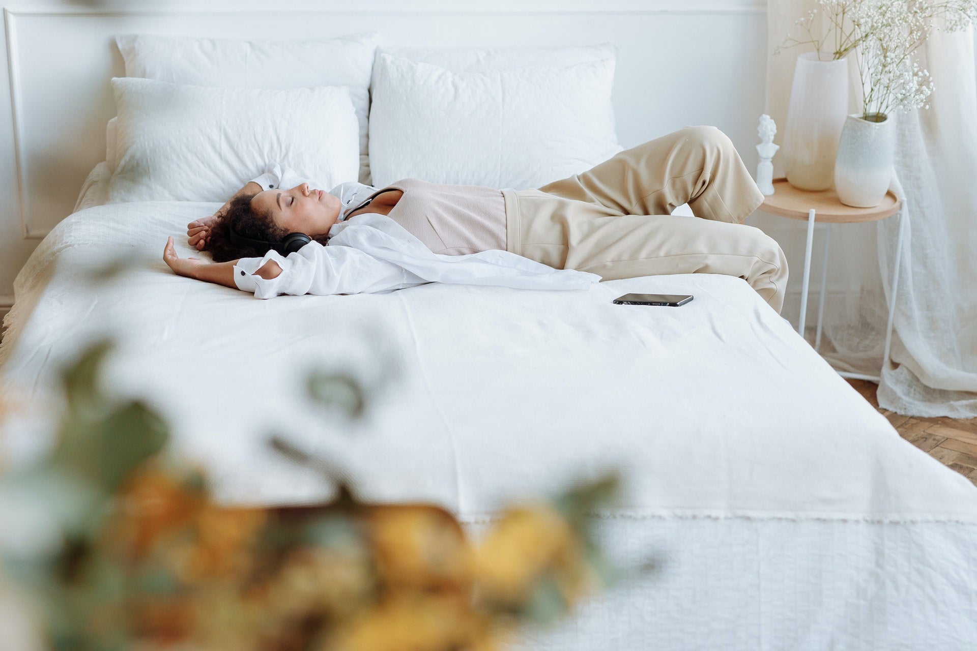 A woman napping in her room, lying sideways on her bed with her phone next to her