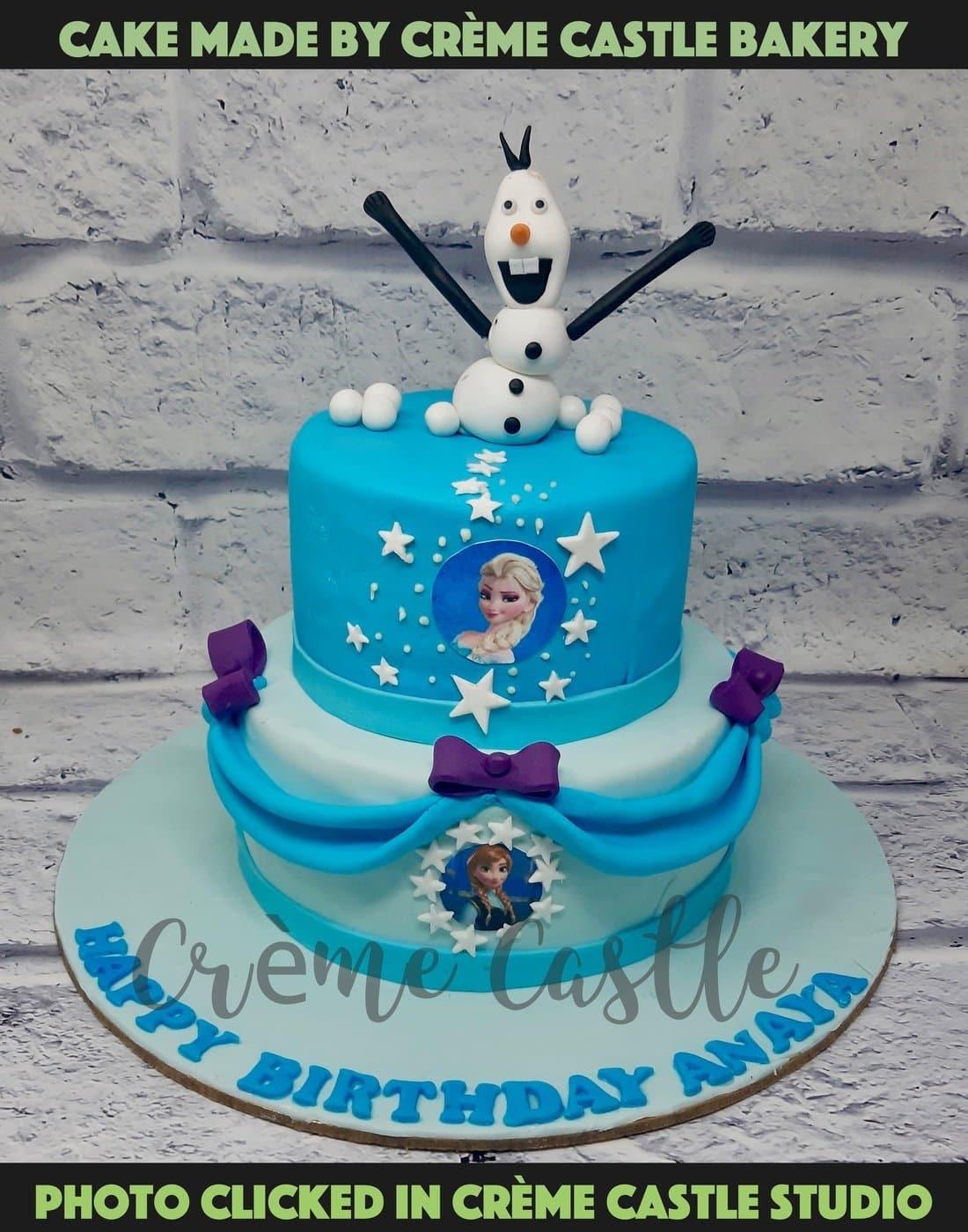 A frozen theme cake with Olaf on top and Elsa in the center with ...