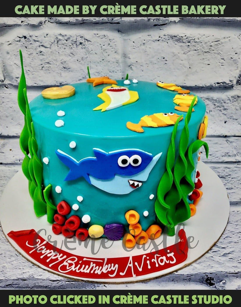 A Baby Shark Theme Cake With Baby Shark Characters On Top And Sides With Underwater Feeling Creme Castle