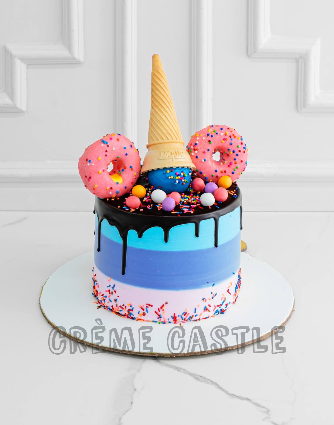 A multi color cake with an inverted cone on top with fondant made ...
