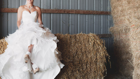 bride sitting on a hay bale at her barn wedding
